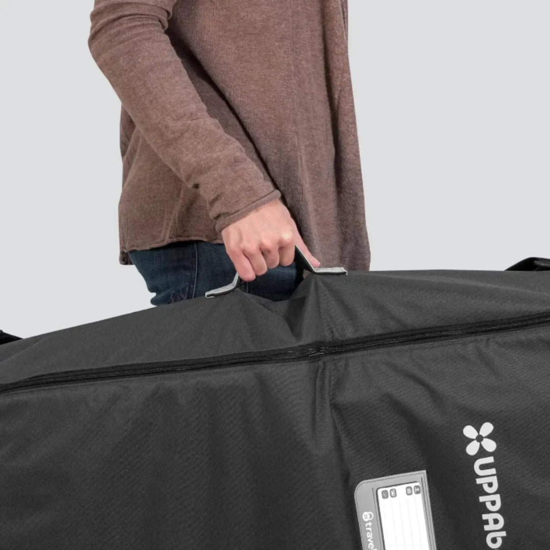 Person holding the UPPAbaby travel bag for Carry Cot and RumbleSeat by the top carry handle.