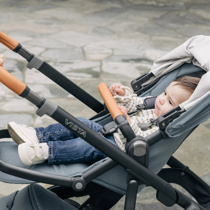 Baby relaxing in a fully reclined UPPAbaby Vista V3 stroller in the Dillian colourway, showing the cushioned toddler seat, leather bumper bar, adjustable recline mechanism and sturdy Vista frame. Lifestyle photo highlighting comfort, support and premium design of the Vista V3 pushchair.
