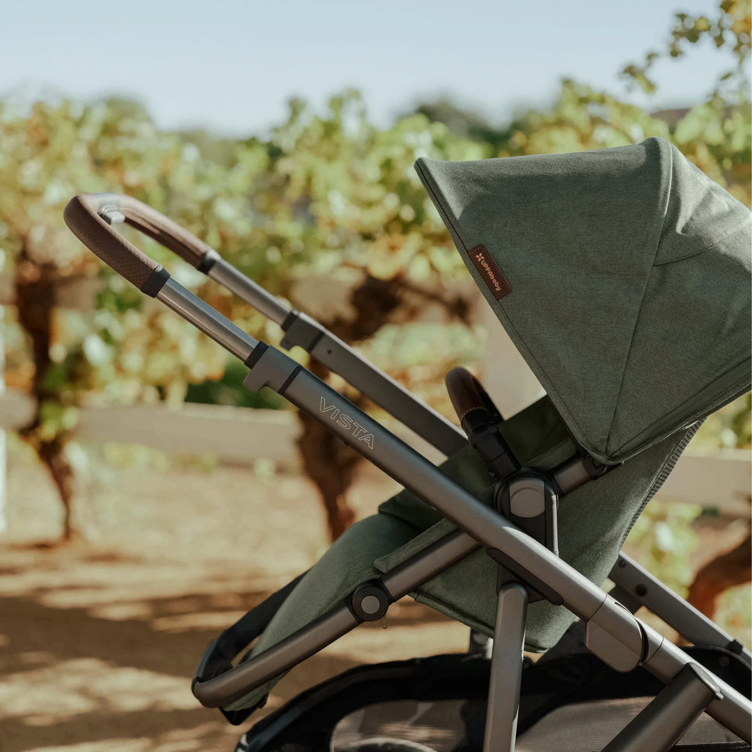 Side view of the UPPAbaby Vista V3 stroller in the Evelyn green colourway outdoors, highlighting the premium extendable canopy, sleek aluminium frame, leather-accented handlebar, and ergonomic seat design.