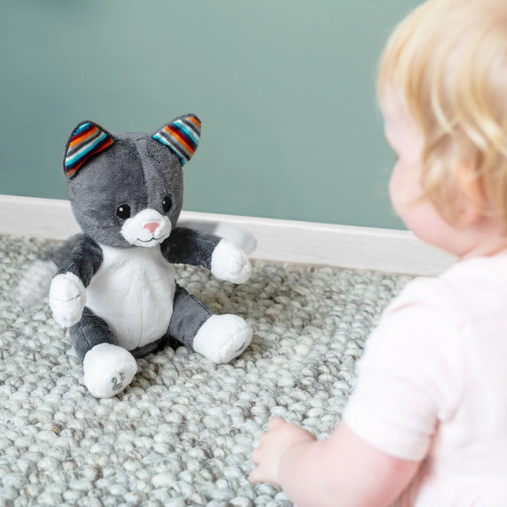 Child playing with a plush toy cat on a carpeted floor