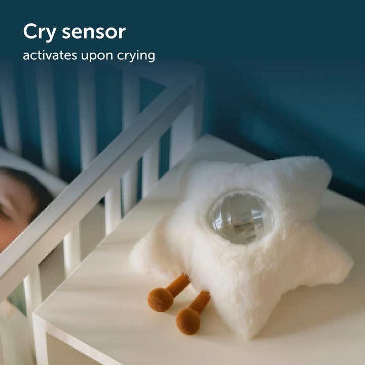 Baby in crib with star-shaped projector and sound machine with cry sensor that activates upon crying