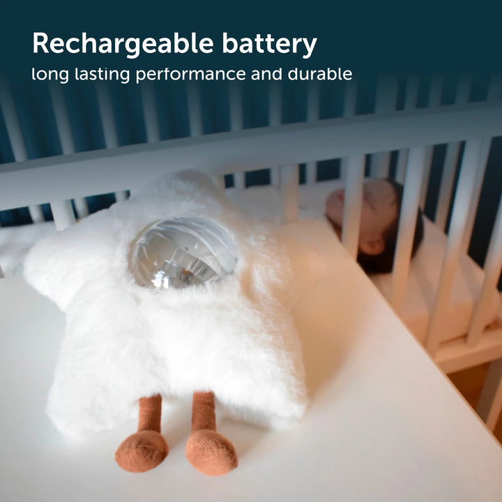 Plush star galaxy projector on table beside baby crib with rechargable battery text overlayed.