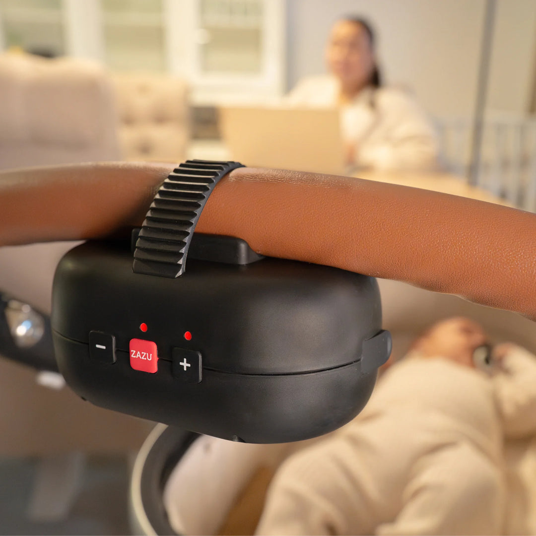 ZAZU Robby the Rocker baby rocker attached to stroller handle gently rocking a sleeping baby while parent works in the background — smart automatic pram rocker designed for hands-free soothing and better baby sleep.