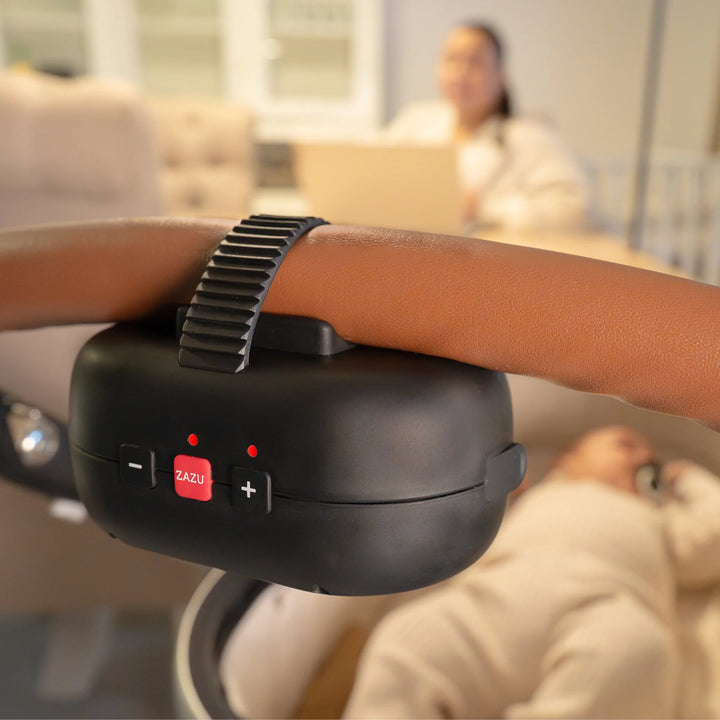 ZAZU Robby the Rocker baby rocker attached to stroller handle gently rocking a sleeping baby while parent works in the background — smart automatic pram rocker designed for hands-free soothing and better baby sleep.