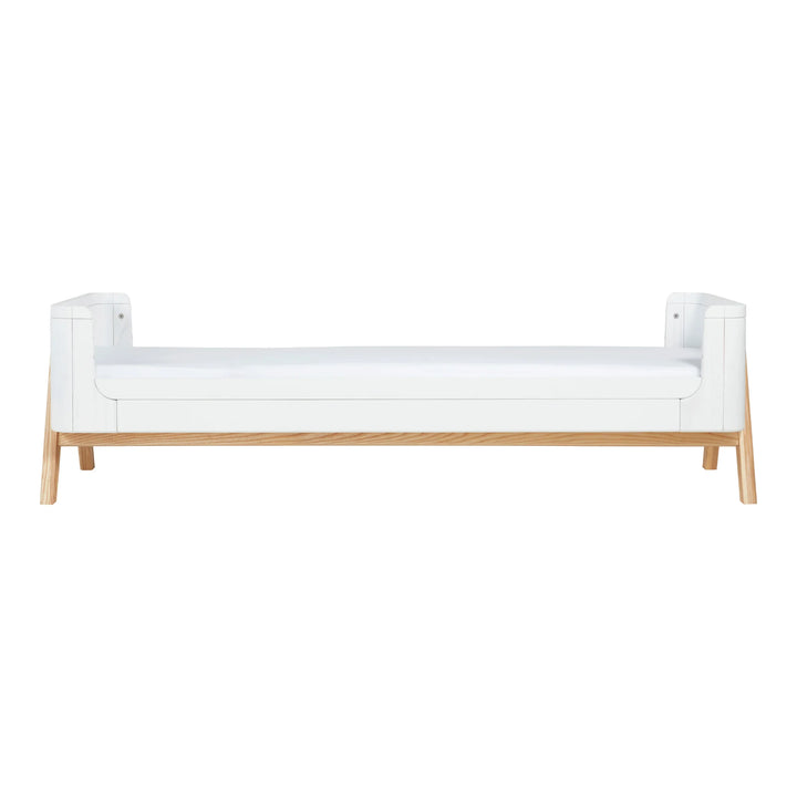 “aia Baby Hera junior bed extension in Scandi white with natural ash wood legs, shown fully extended as a low Montessori-style toddler bed for ages 4–5 years.