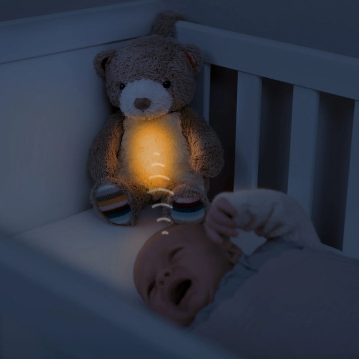 Zazu Bruno Baby Soother – glowing plush teddy bear nightlight soothing a crying baby in cot with calming shushing sounds and warm light, promoting peaceful sleep