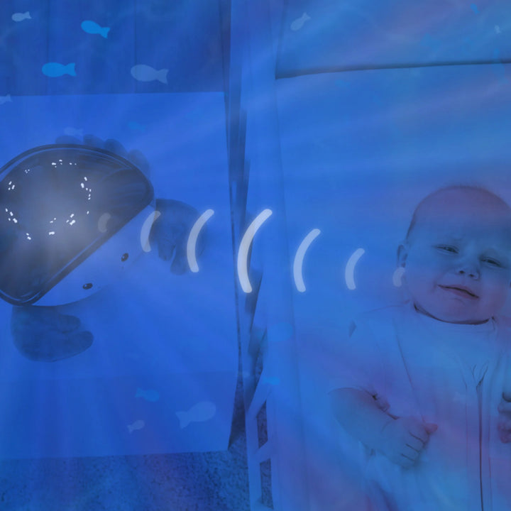 Zazu Cody Ocean Projector – plush crab nightlight projecting soothing ocean waves and calming sounds beside a baby in a cot, helping comfort and lull infants to sleep