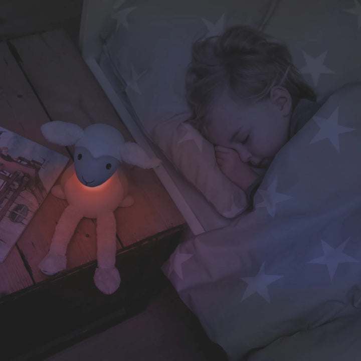 ZAZU Fin the Sheep Nightlight glowing softly beside sleeping child — red light bedtime lamp for toddlers promoting comfort, relaxation, and better sleep routine in kids’ bedroom.