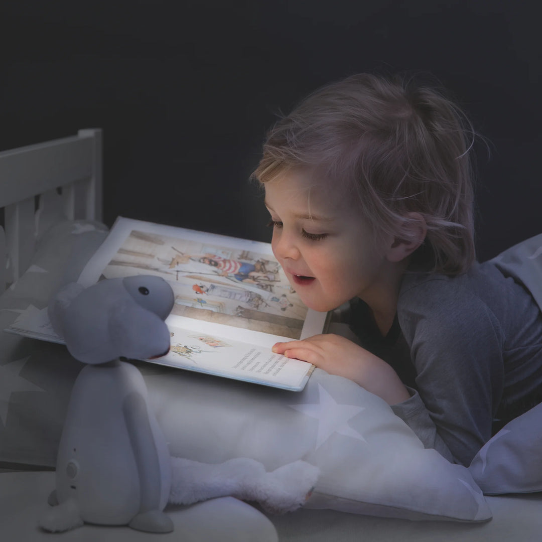 Child reading bedtime story illuminated by ZAZU Fin the Sheep Nightlight — soft LED kids’ night lamp providing gentle light for reading, relaxation, and peaceful bedtime routine.
