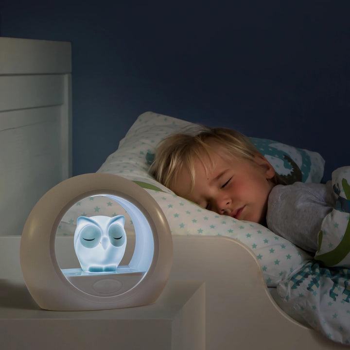 Zazu Lou Nightlight – glowing owl nightlight on bedside table soothing a sleeping child, providing gentle adjustable light with cry sensor for a peaceful night’s sleep.