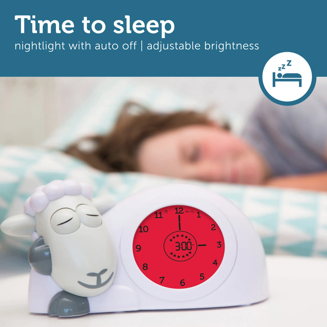 ZAZU Sam the Sheep sleep trainer clock in red bedtime mode, displayed beside a sleeping child, highlighting the nightlight with auto-off and adjustable brightness features.