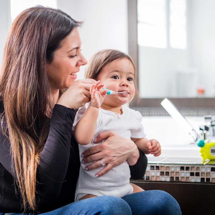 BBLuv Sonik electric toothbrush being used by a mother to help her toddler brush their teeth correctly.