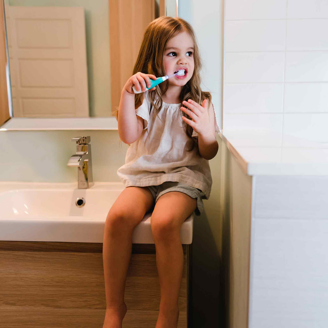 BBLuv sonik electric toothbrush being used by child sitting on the side of the bathroom sink