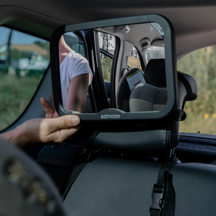 This image shows a parent adjusting the angle of the large rear view mirror