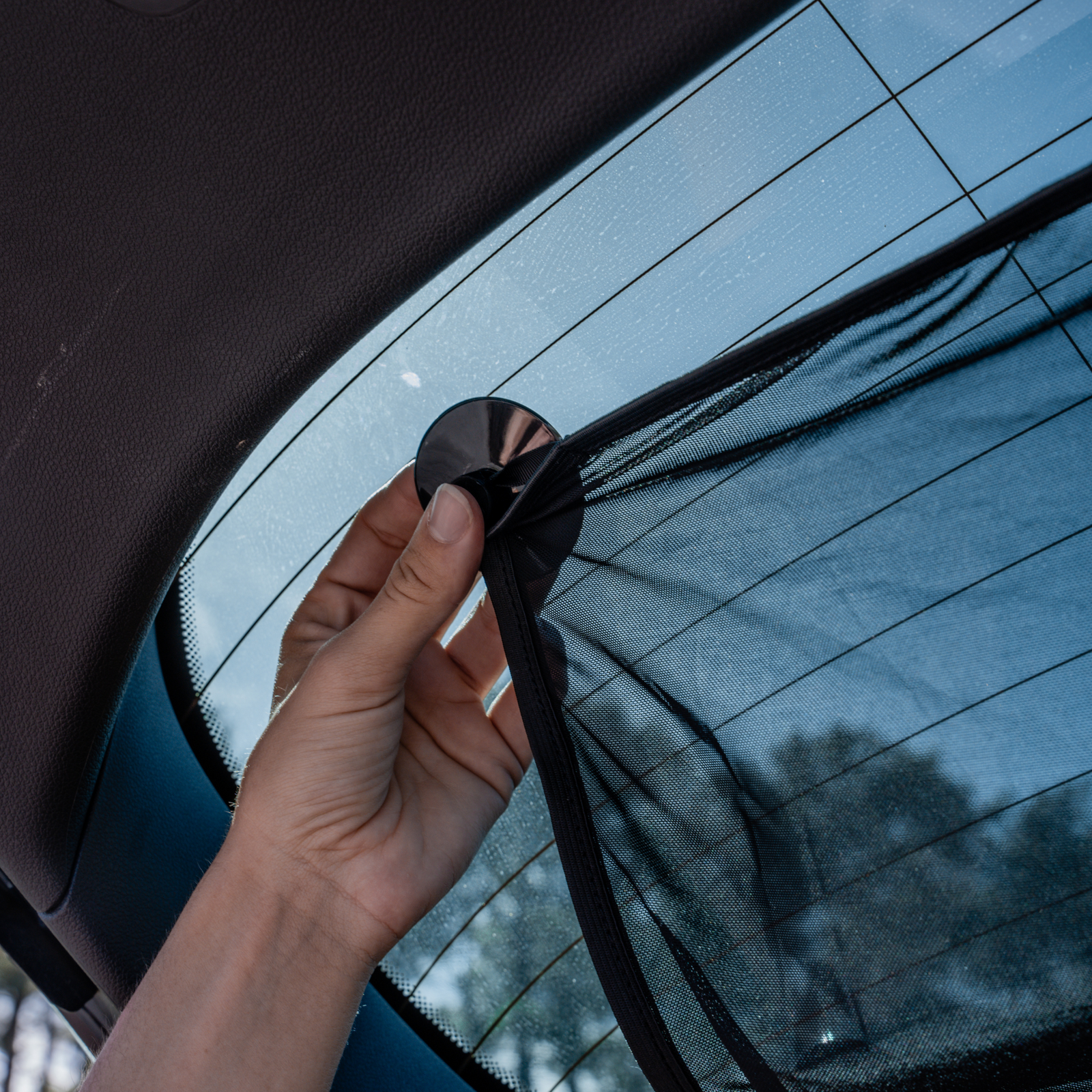 Lifestyle image of parent installing rear windscreen sunshade in car.