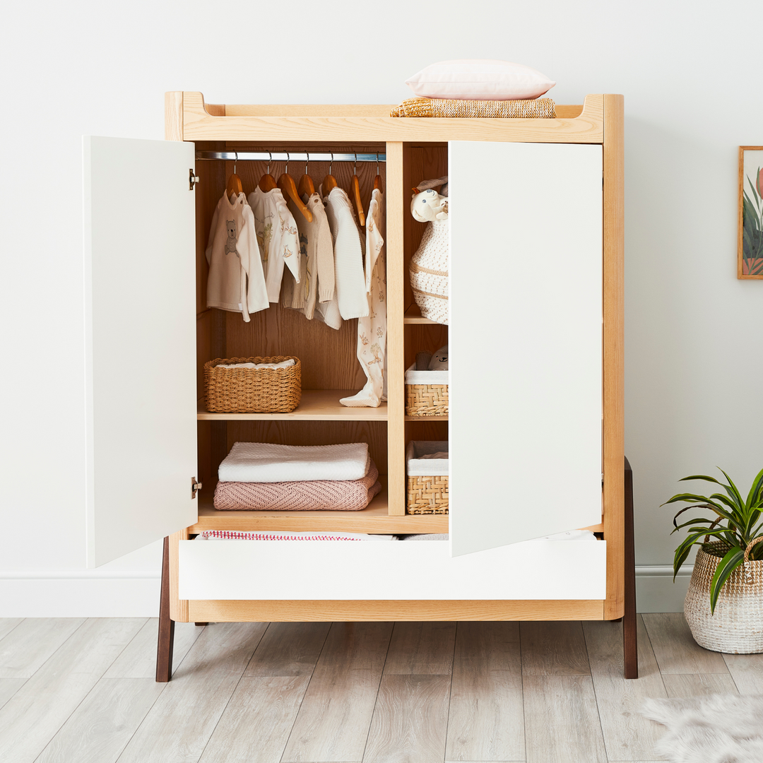 lifestyle image of Gaia Baby Hera Wardrobe in Natural Ash and Walnut with one door being open. 