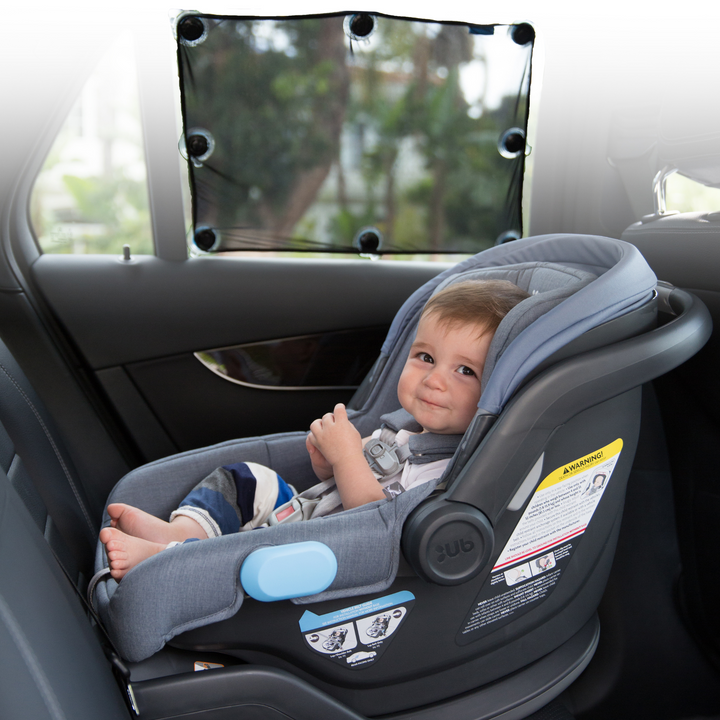 This is an image of the UPPAbaby easy fit sun shade on a car window, protecting a little baby in the car seat from the sun's harmful UV rays