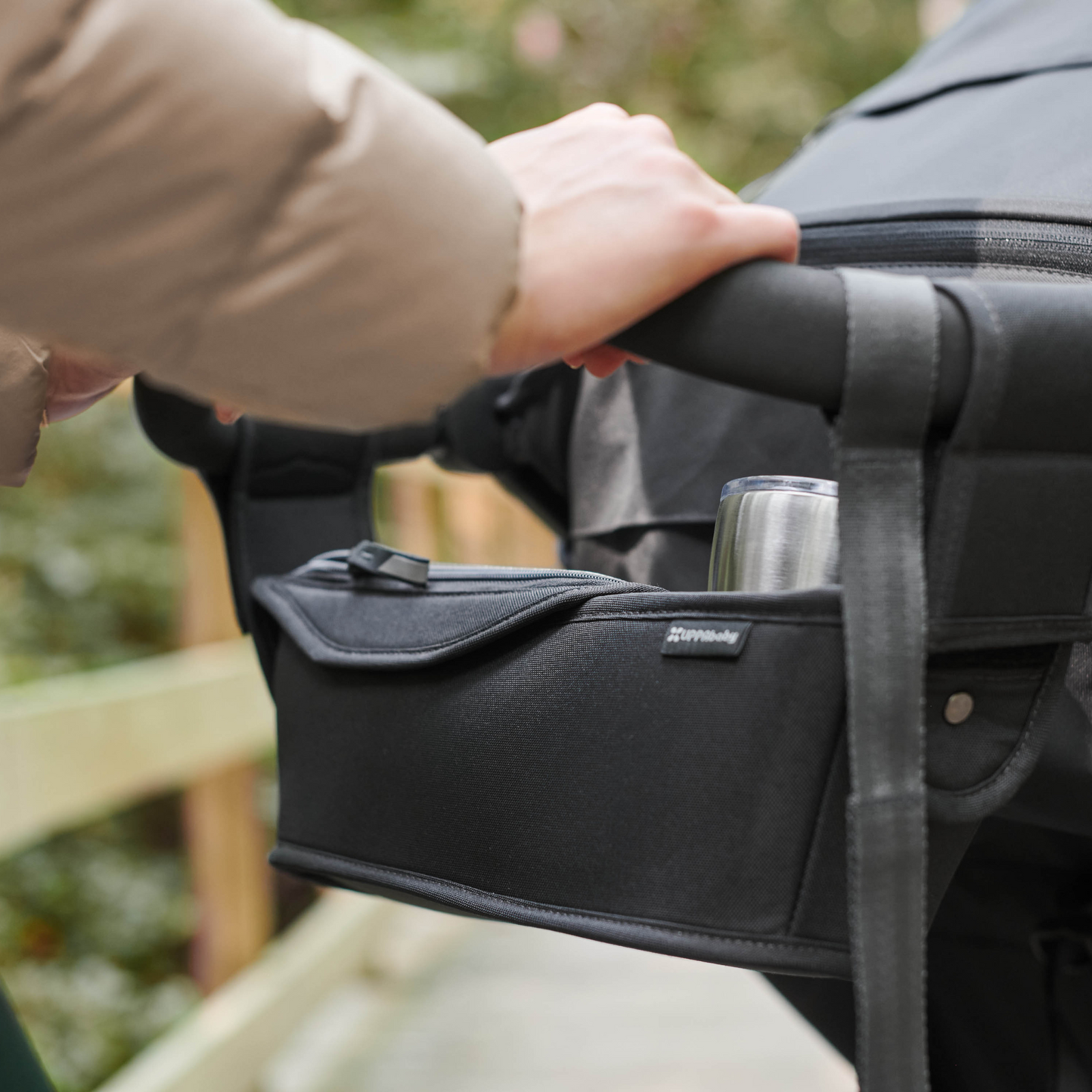 This is a lifestyle shot of the Ridge parent console attached to the Ridge handlebars being used on a forest walk, with a coffee cup in the cup holder slot.